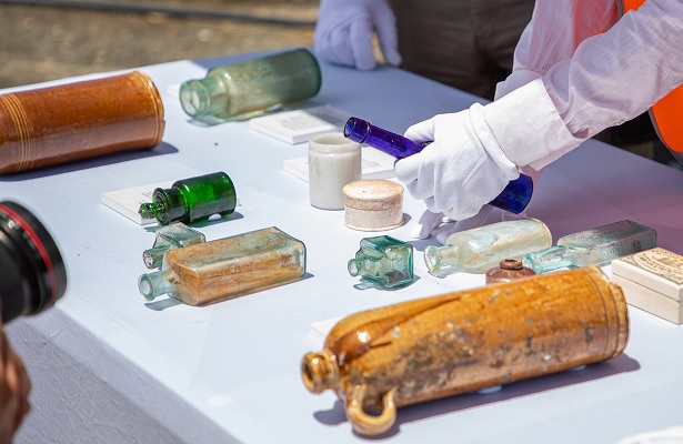 Picture of artefacts placed on a table whilst a gloved hand interacts with them.